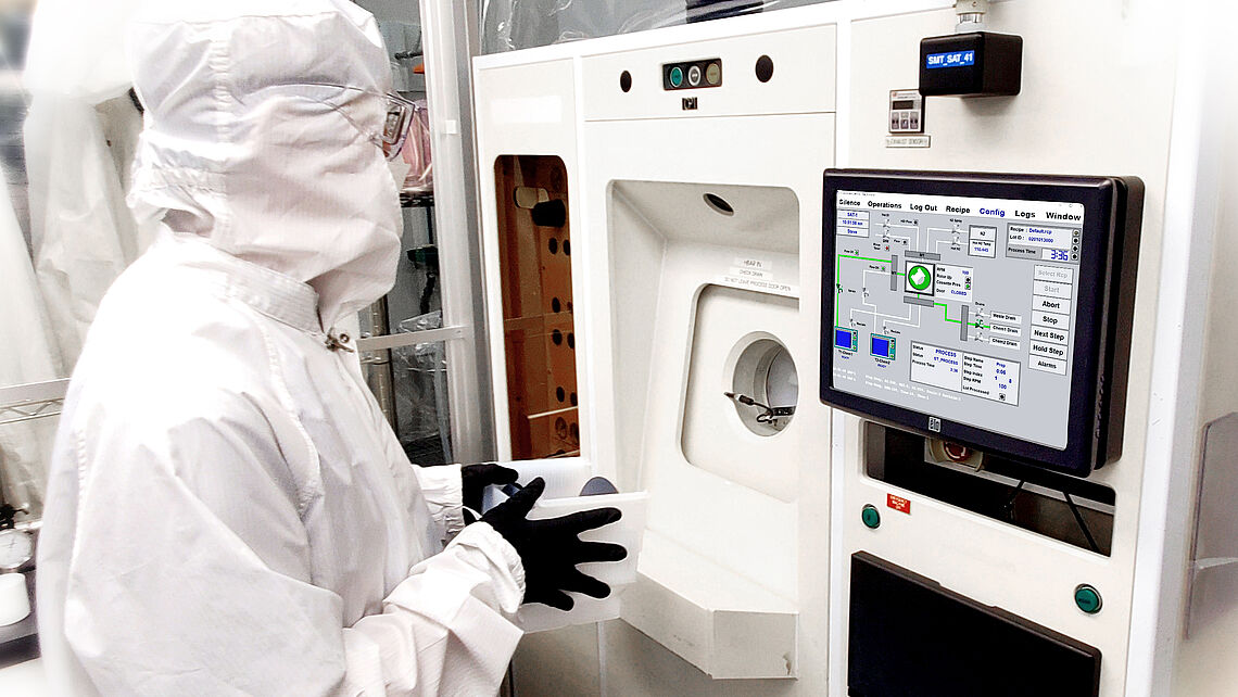 a man at a machine in a protective suit etching process